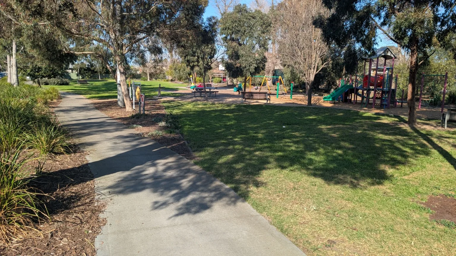 Pathway, open lawn and playground inside Beevers Reserve